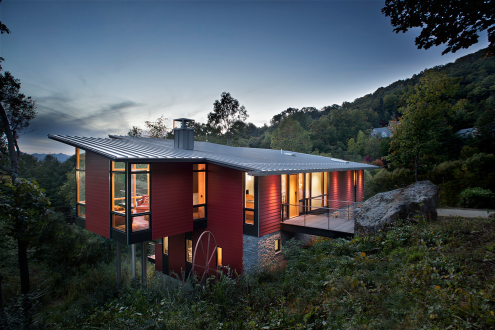Пример оригинального дизайна: красный, двухэтажный, деревянный частный загородный дом в современном стиле с односкатной крышей и металлической крышей
