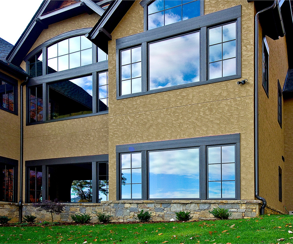 Immagine della facciata di una casa grande beige contemporanea a due piani con rivestimento in stucco e tetto a capanna