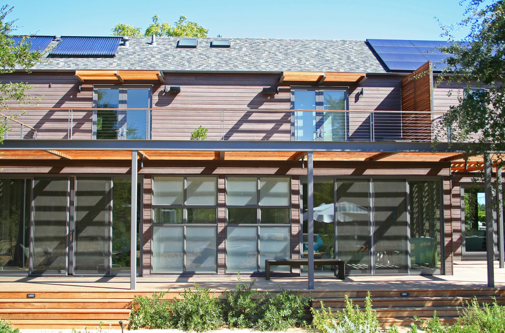 Réalisation d'une grande façade de maison marron minimaliste en bois à un étage.