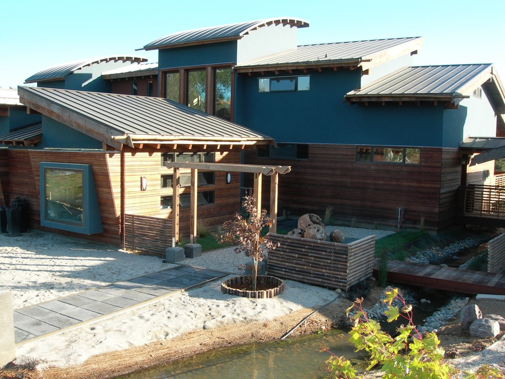 Large and blue world-inspired two floor house exterior in San Francisco with wood cladding and a lean-to roof.