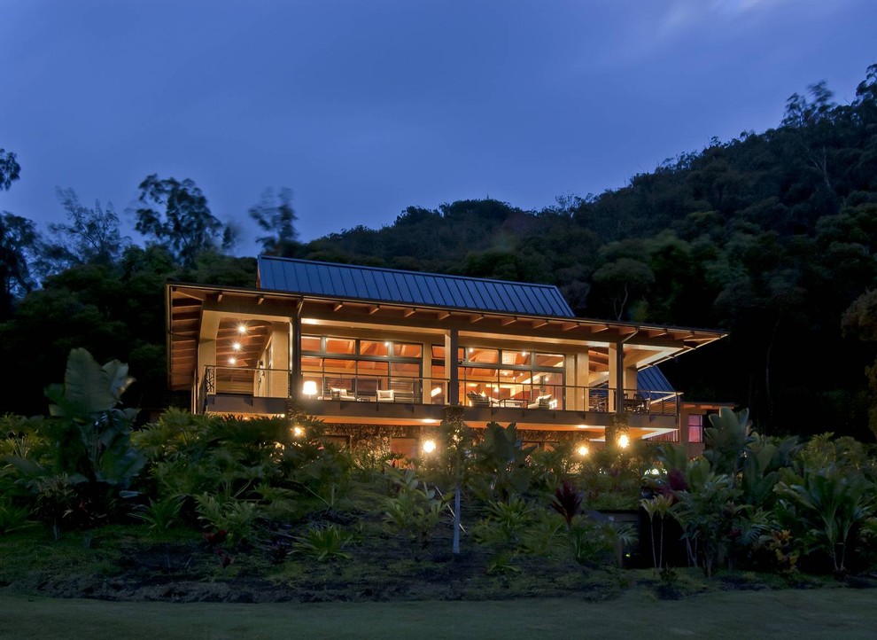 Diseño de fachada de casa beige tropical grande de dos plantas con revestimiento de estuco, tejado a cuatro aguas y tejado de metal