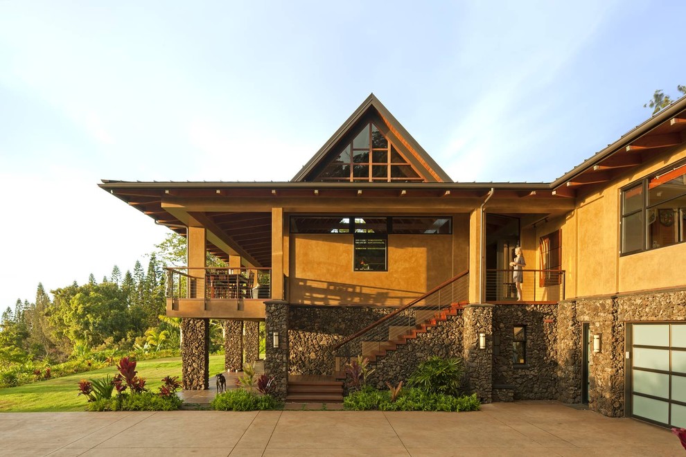 Immagine della villa grande beige tropicale a due piani con rivestimento in stucco, tetto a padiglione e copertura in metallo o lamiera