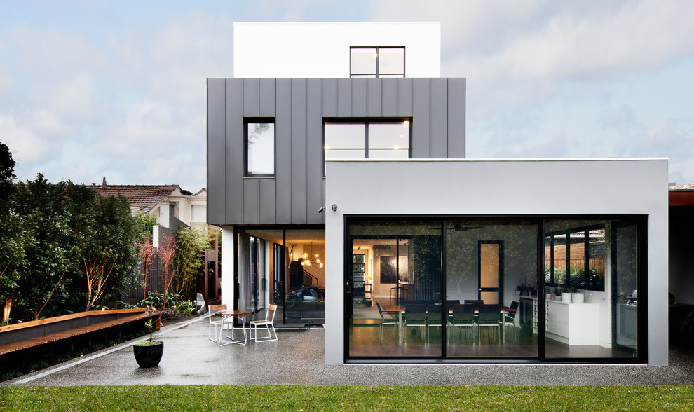Imagen de fachada de casa gris actual grande de tres plantas con tejado plano y tejado de metal