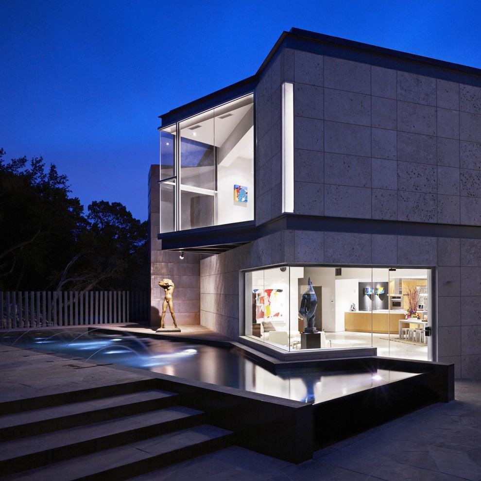 На фото: двухэтажный, большой, серый частный загородный дом в современном стиле с облицовкой из камня, плоской крышей и крышей из смешанных материалов с