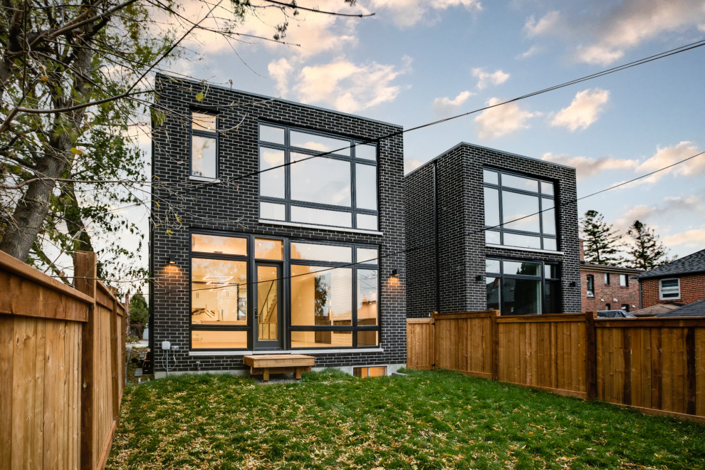 Inspiration pour une petite façade de maison noire minimaliste en brique et planches et couvre-joints à un étage avec un toit plat.