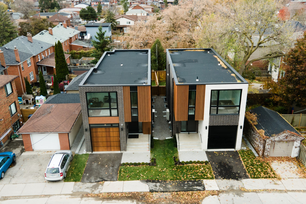 Cette image montre une petite façade de maison noire minimaliste en brique et planches et couvre-joints à un étage avec un toit plat.