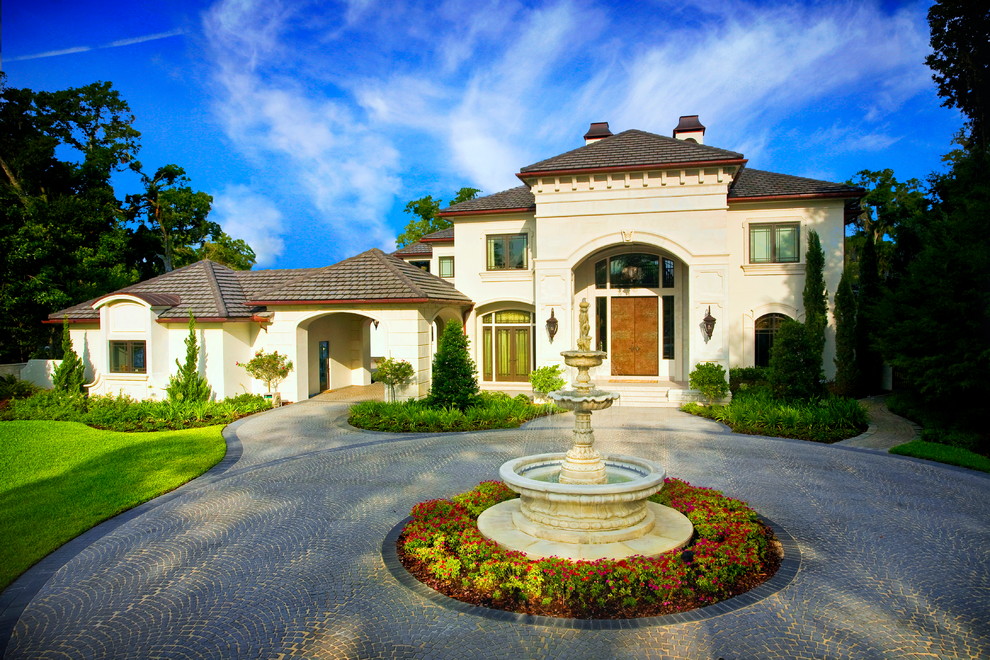 Example of a large tuscan white two-story stucco house exterior design in Orlando with a hip roof and a shingle roof