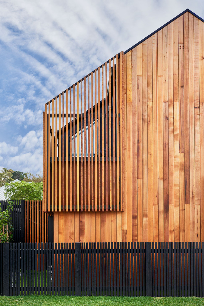 This is an example of a black contemporary two floor terraced house in Geelong with wood cladding, a pitched roof and a metal roof.