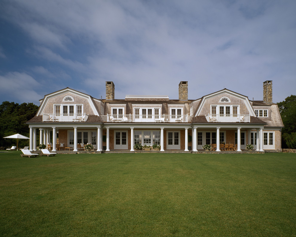 This is an example of an expansive victorian two floor house exterior in Boston with wood cladding and a mansard roof.