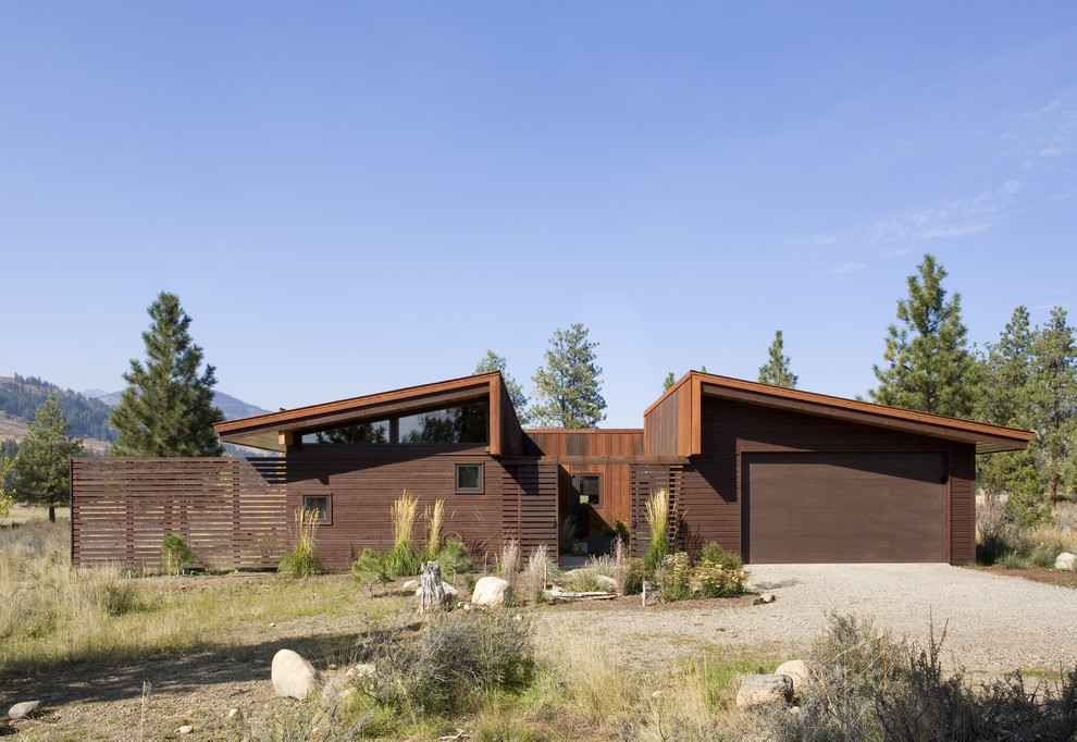 Пример оригинального дизайна: одноэтажный, коричневый дом среднего размера в стиле модернизм с облицовкой из металла и односкатной крышей для охотников