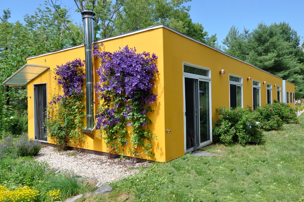 Aménagement d'une façade de maison jaune contemporaine en stuc de taille moyenne et de plain-pied.