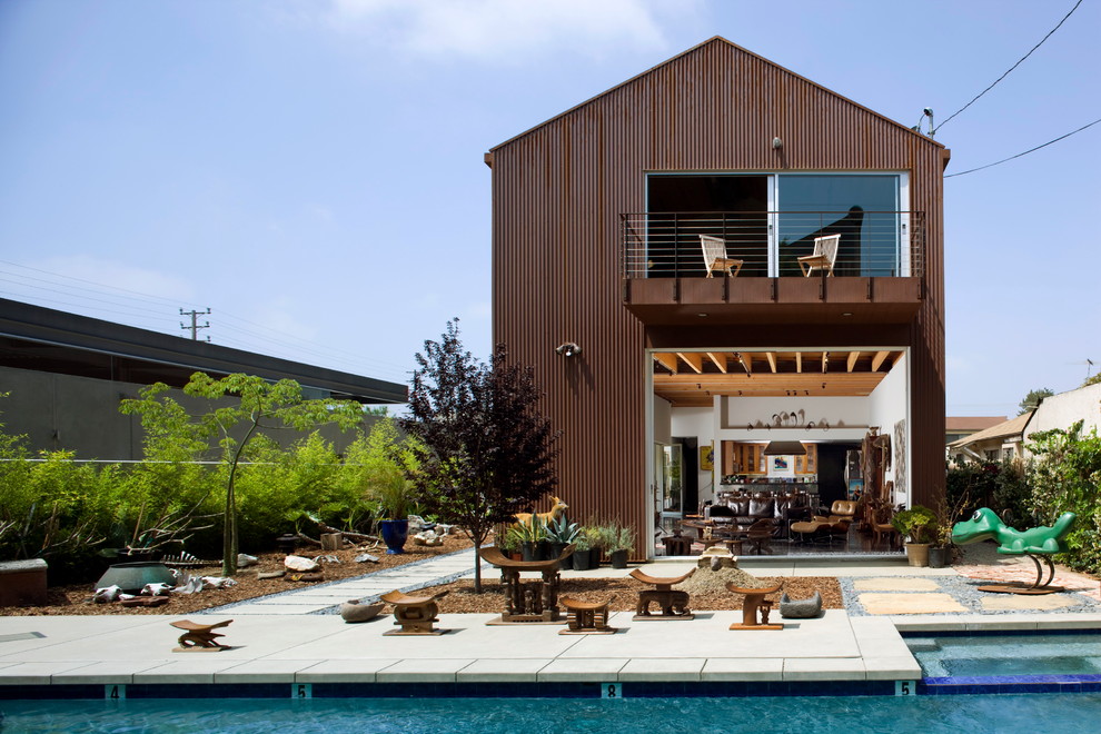 Стильный дизайн: двухэтажный, красный частный загородный дом в стиле модернизм с облицовкой из металла, двускатной крышей и металлической крышей - последний тренд