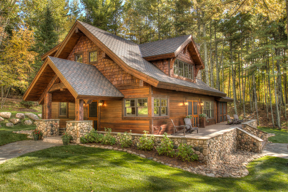 На фото: двухэтажный, деревянный, коричневый частный загородный дом в стиле рустика с двускатной крышей и крышей из гибкой черепицы