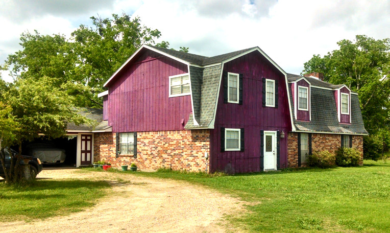 Immagine della facciata di una casa grande rossa country a due piani con rivestimento in legno