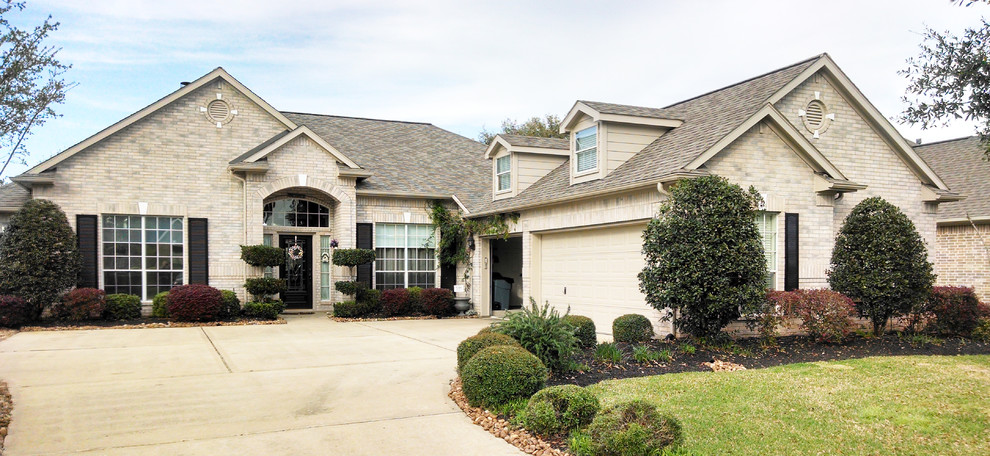 Example of a large classic gray one-story brick exterior home design in Houston