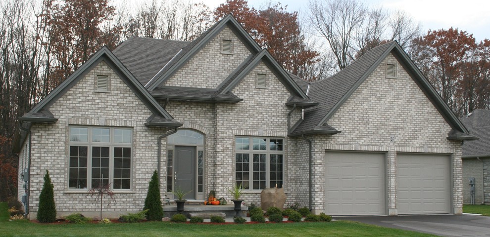 Photo of a gey and medium sized classic house exterior in Toronto with stone cladding and a lean-to roof.