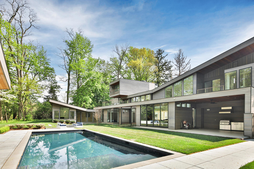 Large and gey contemporary detached house in New York with wood cladding and a flat roof.