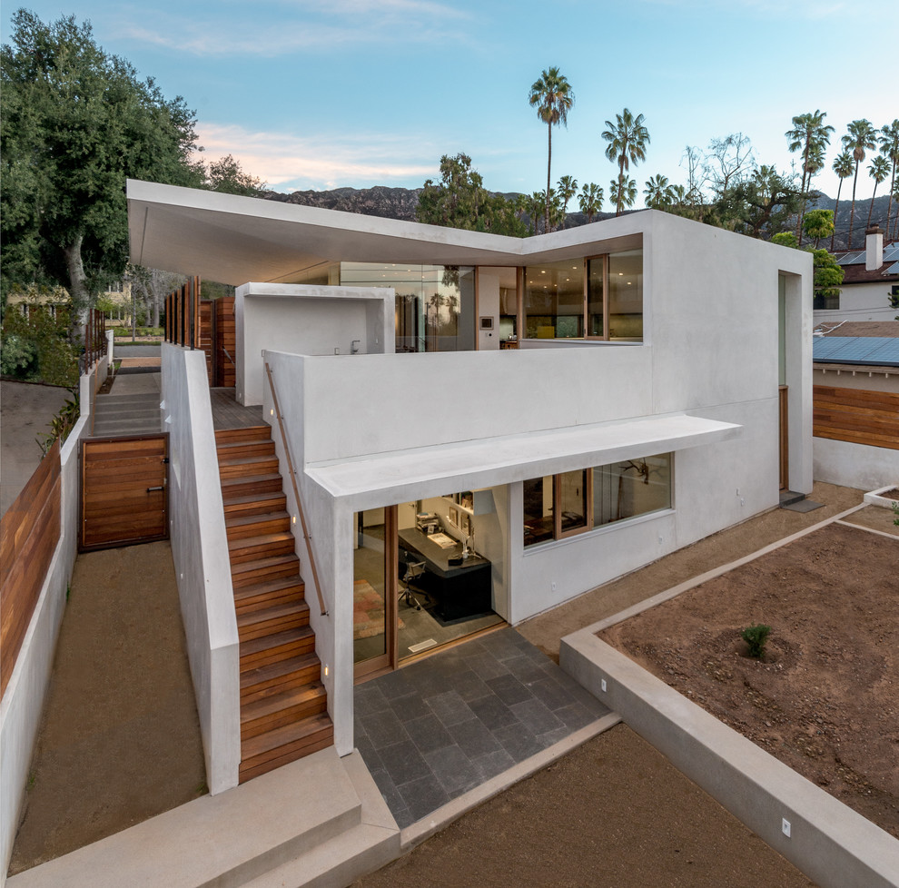 Large and white contemporary two floor render detached house in Los Angeles with a flat roof and a green roof.
