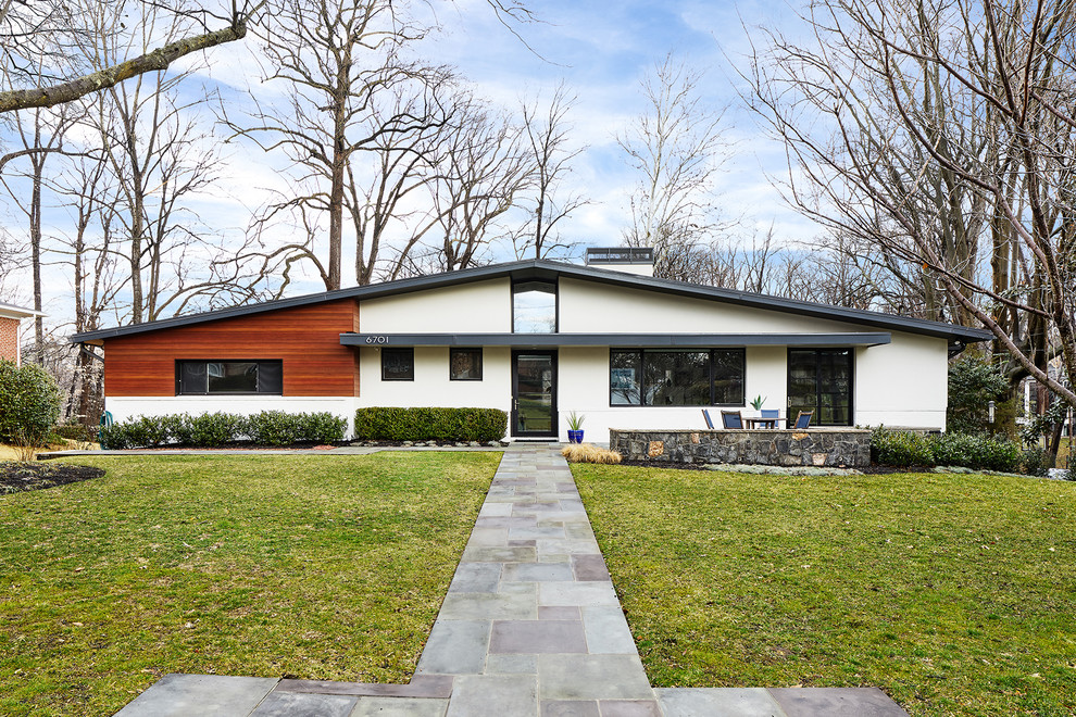 На фото: одноэтажный, серый частный загородный дом среднего размера в стиле ретро с облицовкой из цементной штукатурки, двускатной крышей и металлической крышей