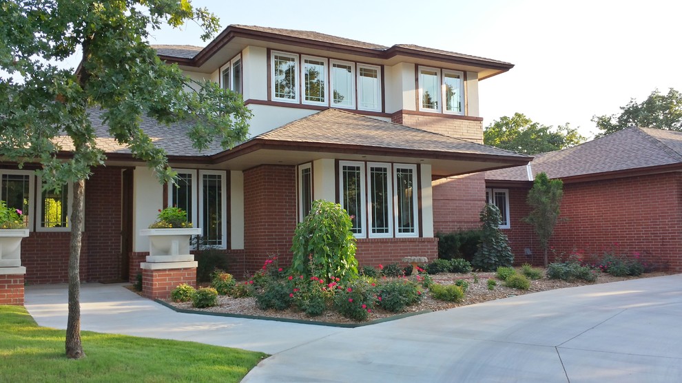 Medium sized and red traditional two floor brick house exterior in Oklahoma City with a hip roof.