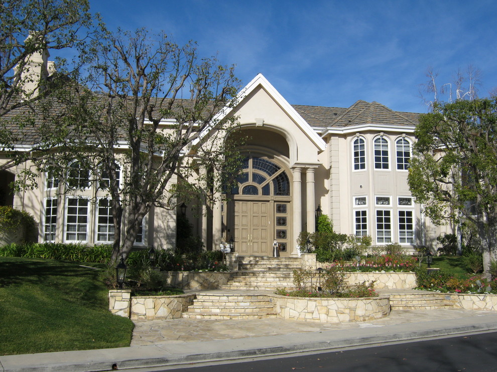 На фото: большой, двухэтажный, бежевый дом в стиле модернизм с облицовкой из цементной штукатурки