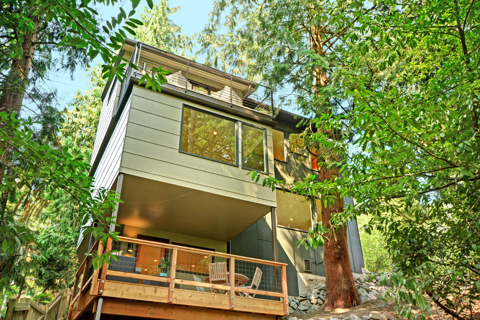This is an example of a large and green modern house exterior in Seattle with three floors, wood cladding and a lean-to roof.