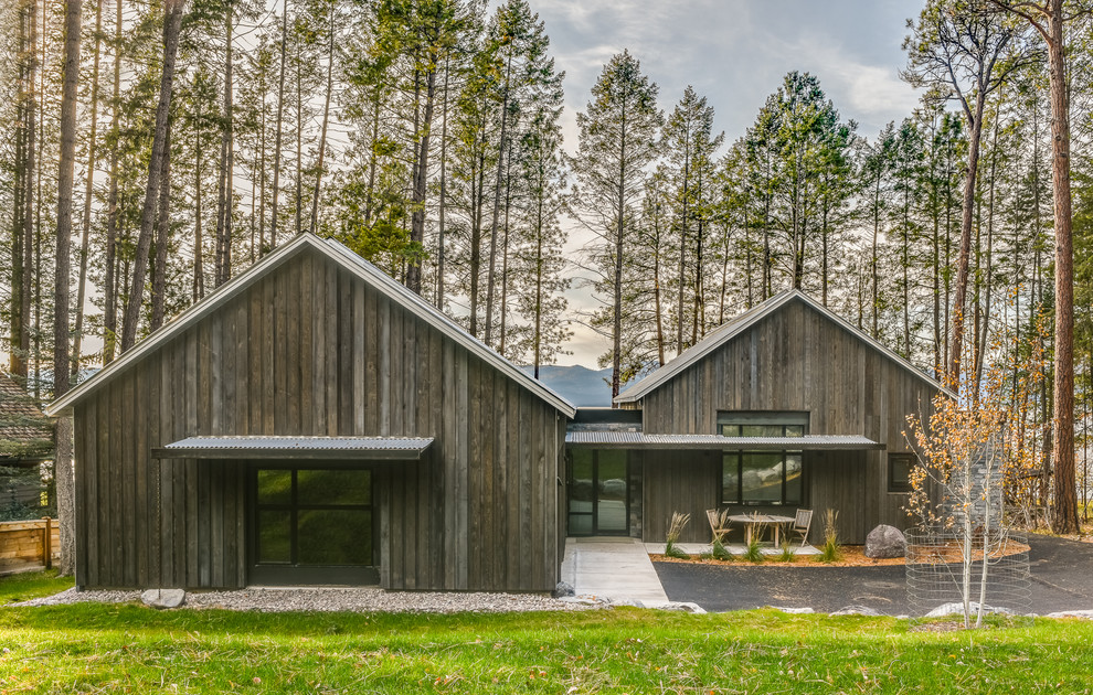 Cette photo montre une grande façade de maison marron montagne en bois de plain-pied avec un toit à deux pans et un toit en métal.
