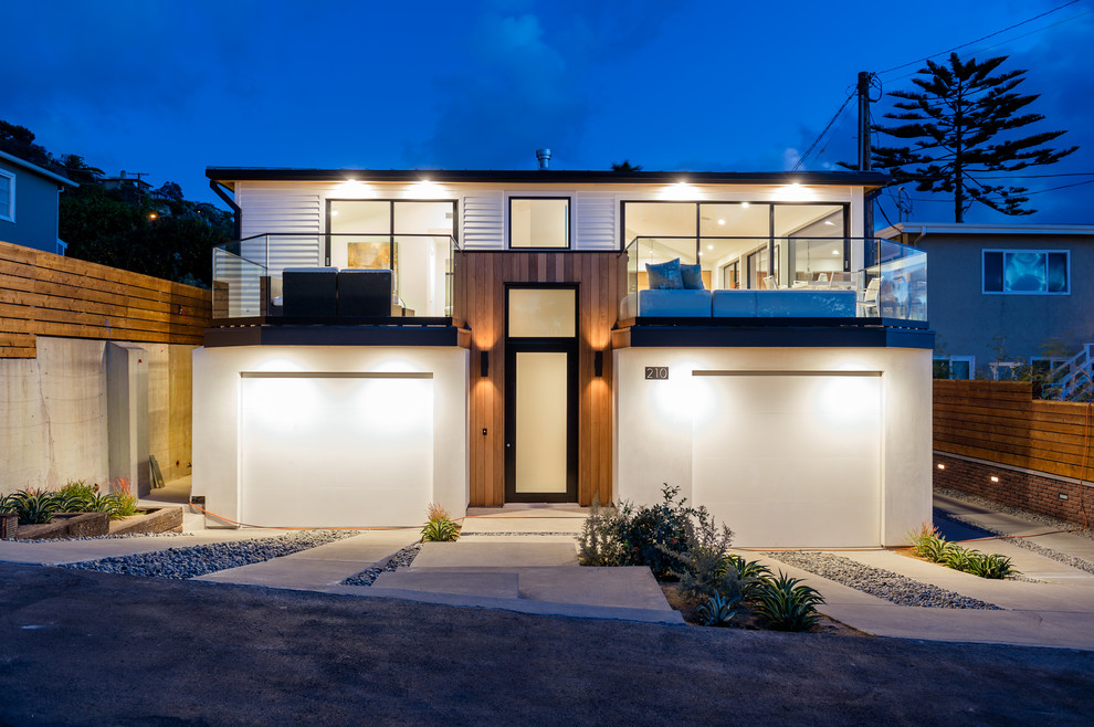 Réalisation d'une façade de maison blanche en bois de taille moyenne et à un étage avec un toit à quatre pans, un toit en métal et un toit gris.