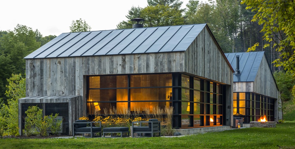 На фото: одноэтажный, деревянный, серый частный загородный дом среднего размера в современном стиле с двускатной крышей и металлической крышей