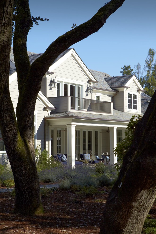 Imagen de fachada de casa blanca campestre grande de dos plantas con tejado a dos aguas, revestimiento de aglomerado de cemento y tejado de teja de madera