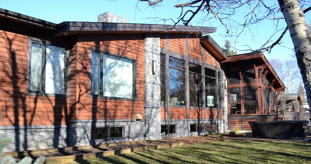 Cette image montre une grande façade de maison marron design à un étage avec un revêtement mixte et un toit en appentis.