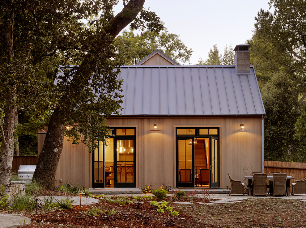 Idée de décoration pour une façade de maison tradition en bois avec un toit à deux pans et un toit en métal.