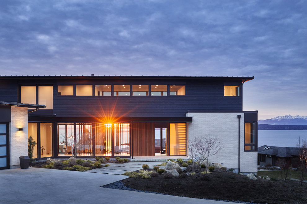 Diseño de fachada de casa negra moderna de tamaño medio de tres plantas con revestimiento de madera y tejado de un solo tendido