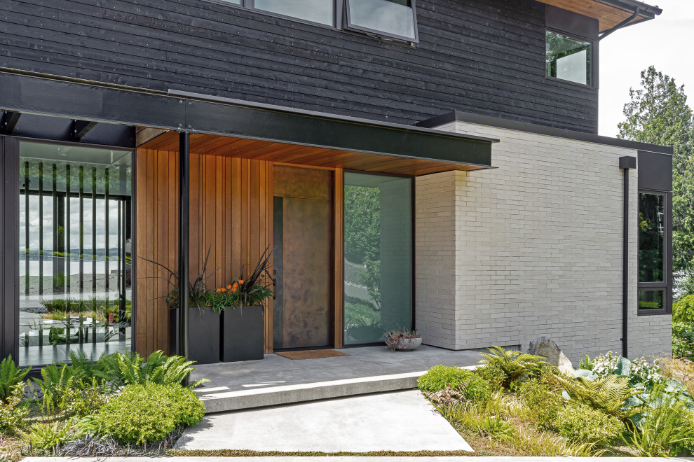 Modelo de fachada de casa negra minimalista de tamaño medio de tres plantas con revestimiento de madera y tejado de un solo tendido