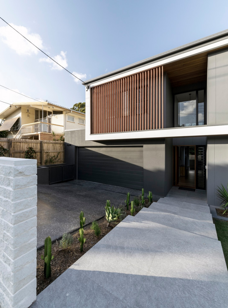 Cette image montre une façade de maison grise design à un étage avec un toit à quatre pans et un toit en métal.