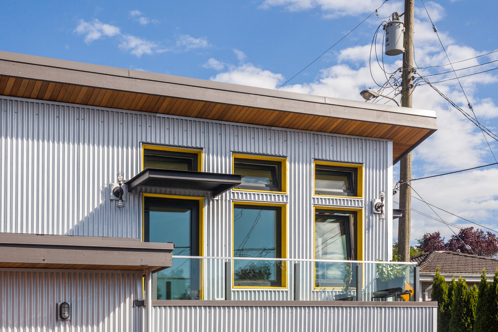 Esempio della facciata di una casa grigia industriale a due piani di medie dimensioni con rivestimento in metallo e copertura in metallo o lamiera