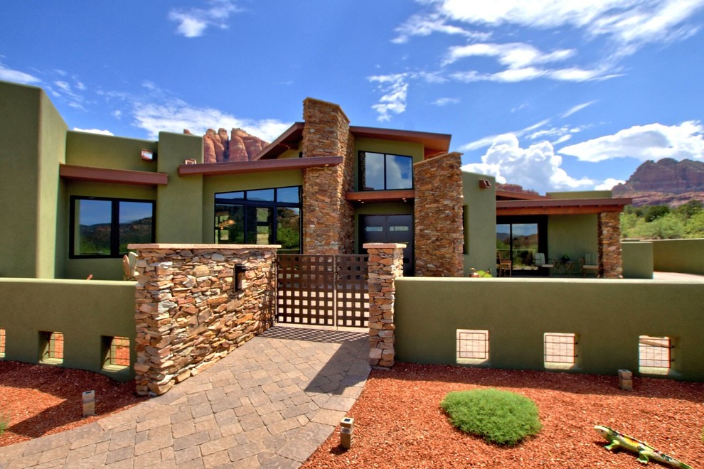 Cette image montre une grande façade de maison verte sud-ouest américain en pierre de plain-pied avec un toit à deux pans.