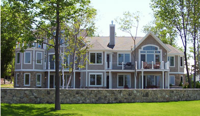 Cette image montre une grande façade de maison grise marine en bois à deux étages et plus avec un toit à deux pans.