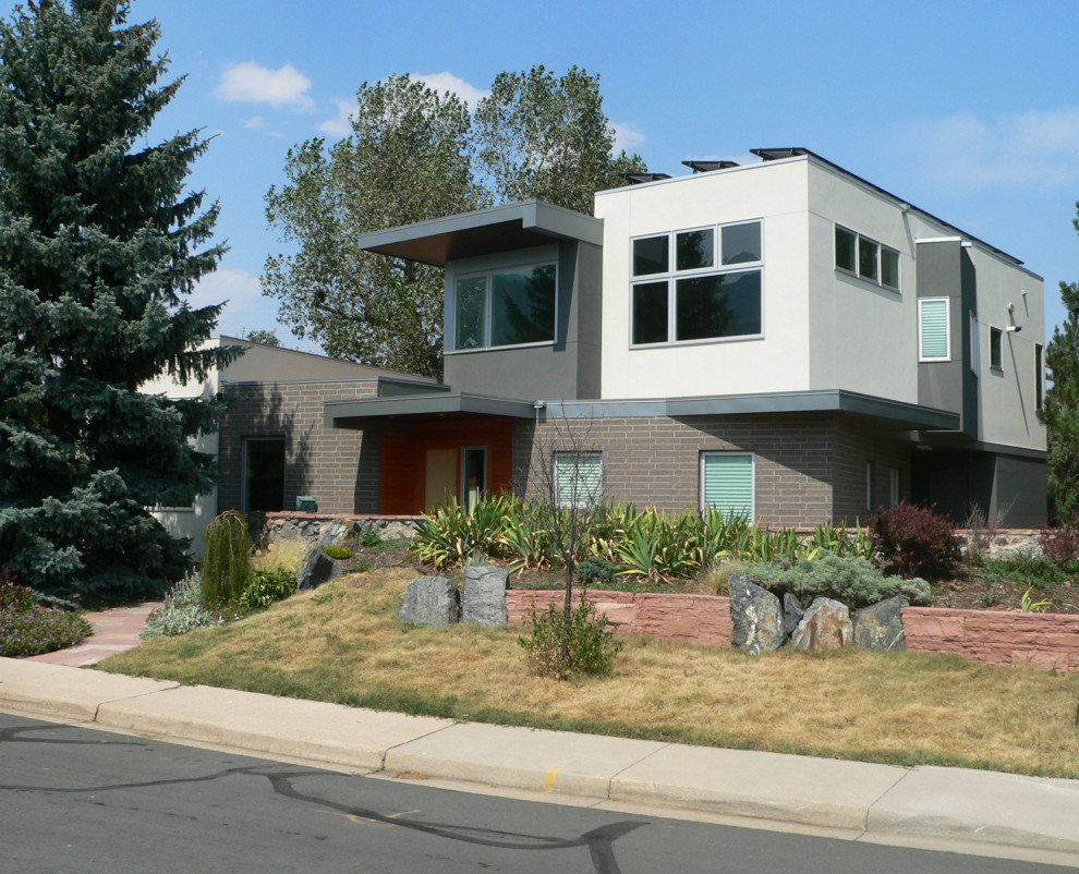 Imagen de fachada de casa gris moderna de tamaño medio de dos plantas con revestimiento de estuco, tejado plano y tejado de varios materiales