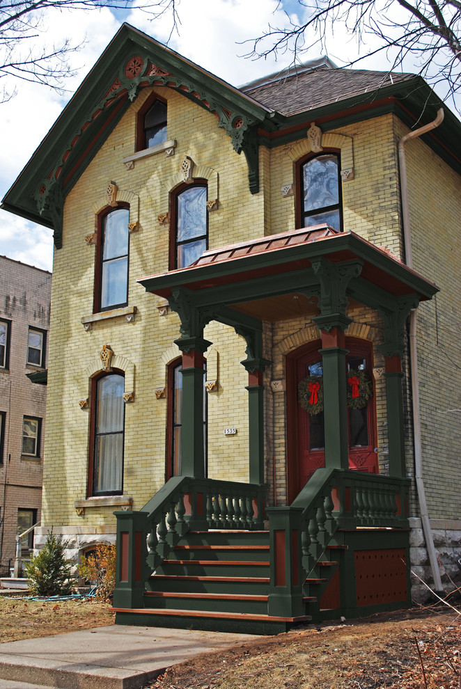 ニューヨークにある低価格のヴィクトリアン調のおしゃれな家の外観 (レンガサイディング、黄色い外壁) の写真