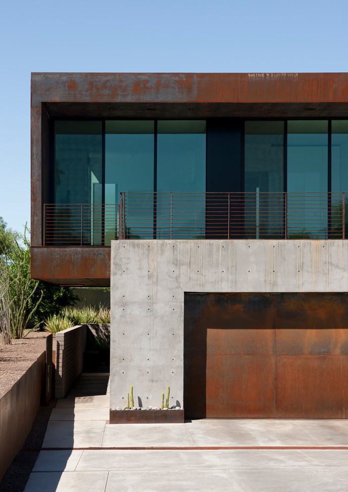 Imagen de fachada gris minimalista de tamaño medio a niveles con revestimiento de metal y tejado plano