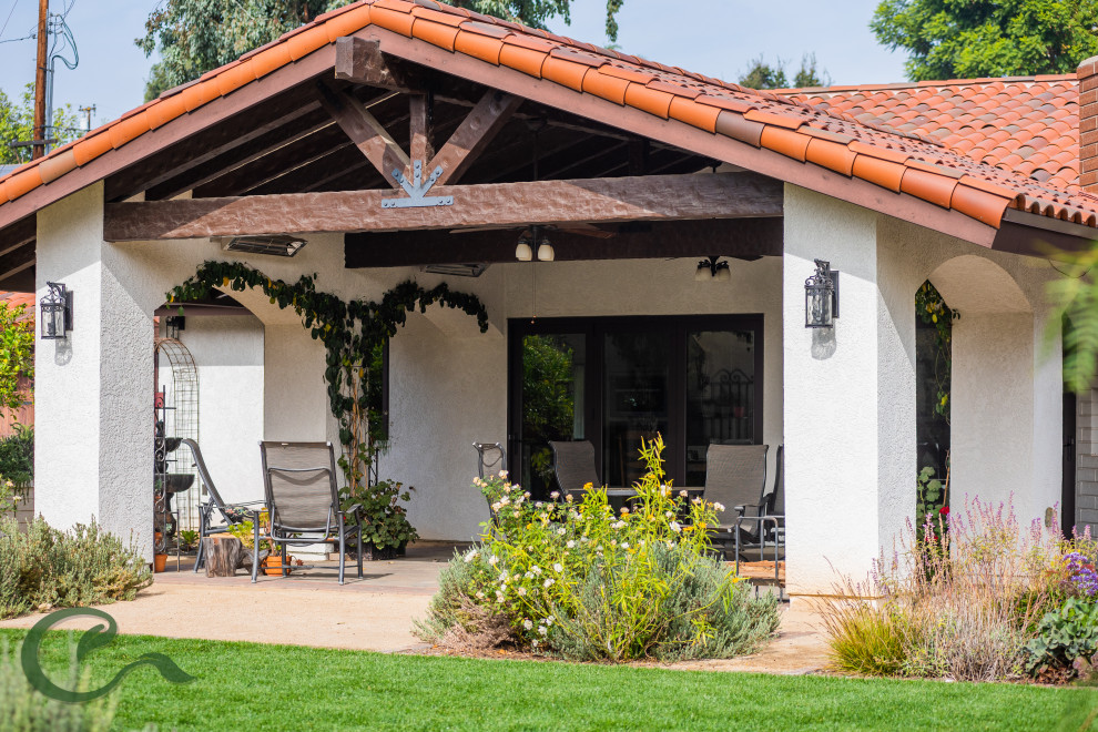 Immagine di un grande patio o portico mediterraneo dietro casa con un caminetto, graniglia di granito e un tetto a sbalzo