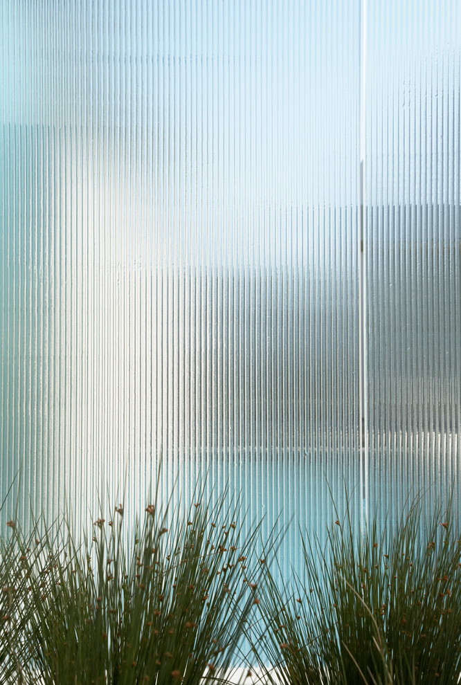 Cette image montre une façade de maison minimaliste en verre à deux étages et plus avec un toit plat.