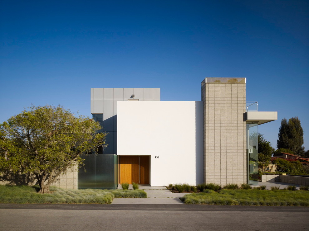 Cette photo montre une façade de maison blanche moderne en béton à deux étages et plus avec un toit plat.