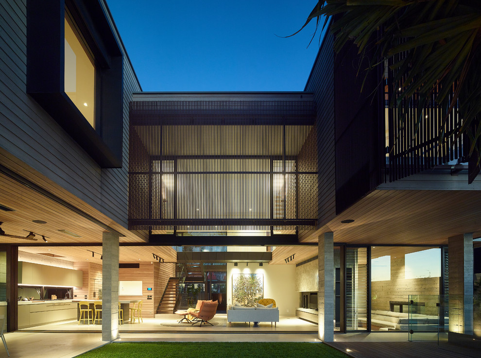 Immagine della villa beige contemporanea a due piani con rivestimento in legno e tetto piano