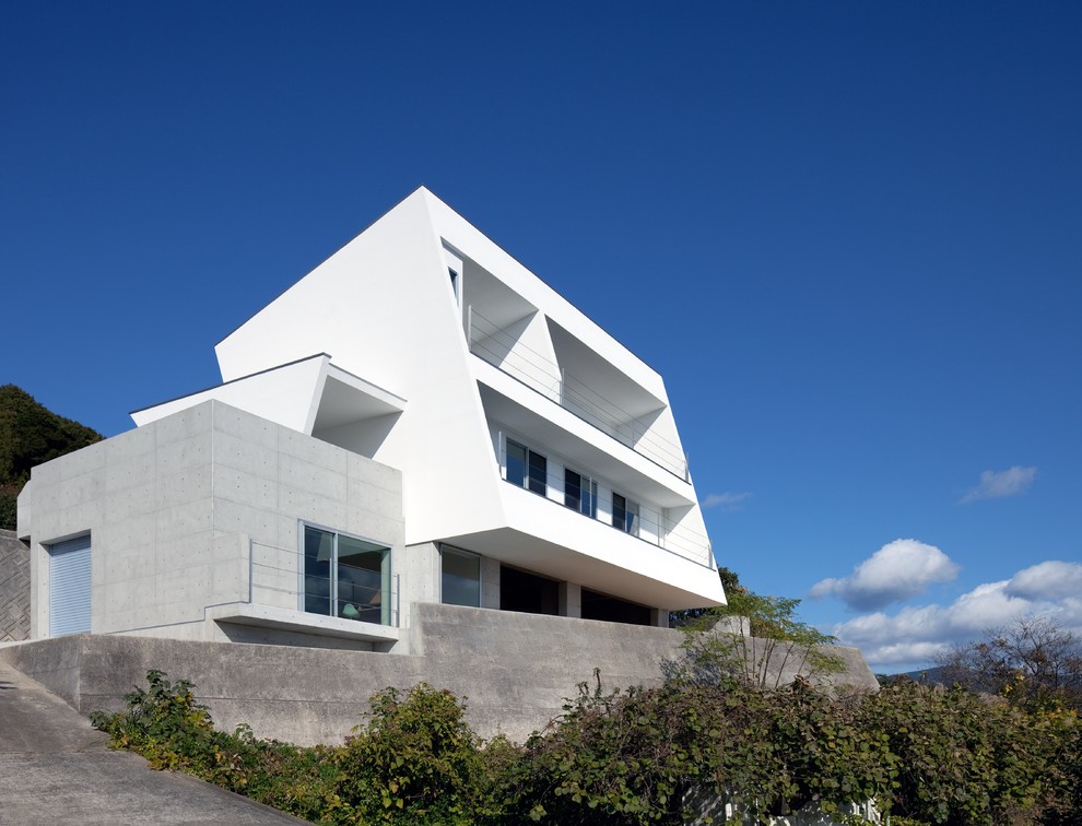 Modern inredning av ett vitt hus i flera nivåer, med blandad fasad och platt tak