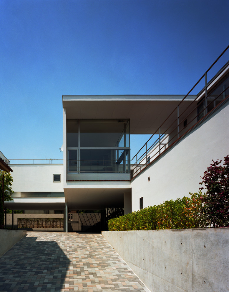 На фото: большой, двухэтажный, белый многоквартирный дом в стиле ретро с облицовкой из цементной штукатурки и плоской крышей с