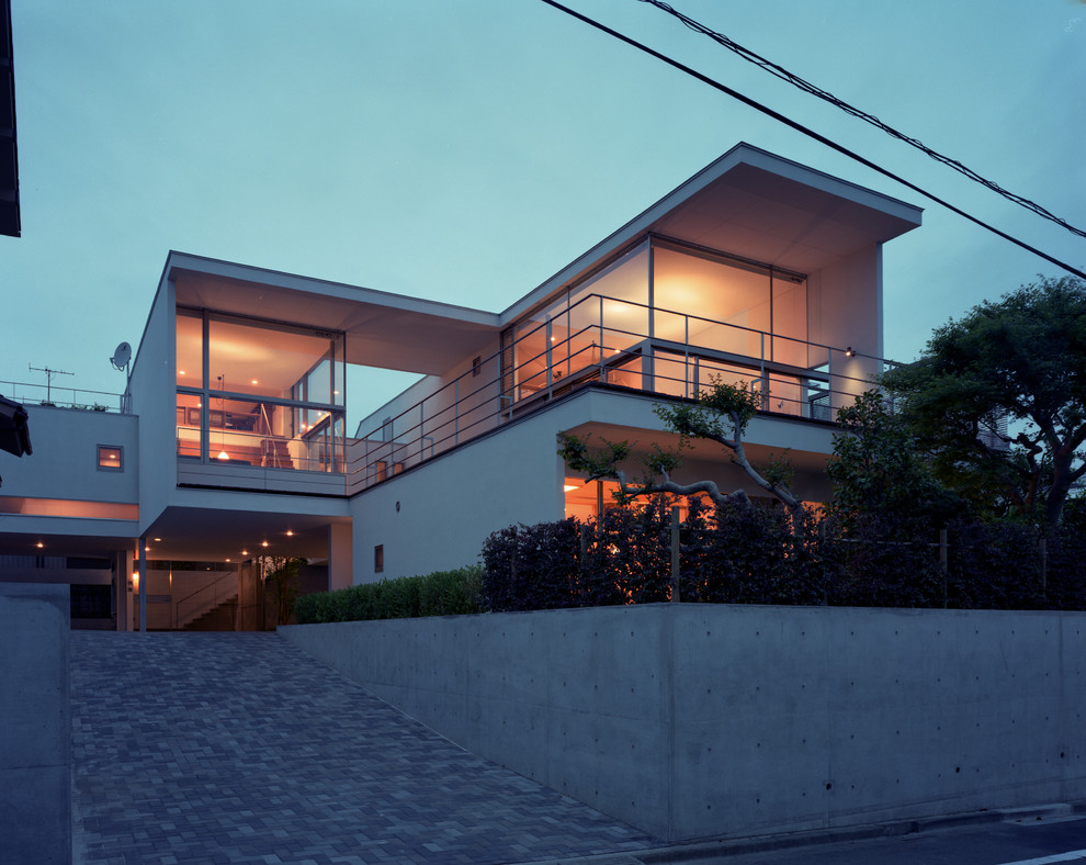 Пример оригинального дизайна: большой, двухэтажный, белый многоквартирный дом в стиле ретро с облицовкой из цементной штукатурки и плоской крышей