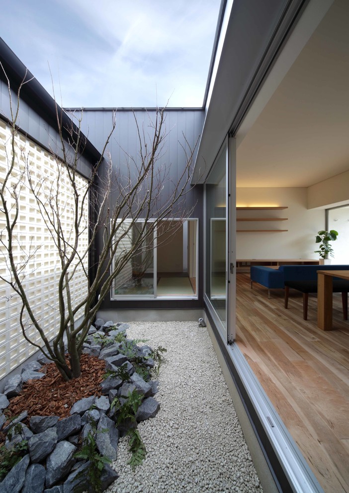 Réalisation d'une petite façade de maison métallique et noire minimaliste à un étage avec un toit en appentis et un toit en métal.
