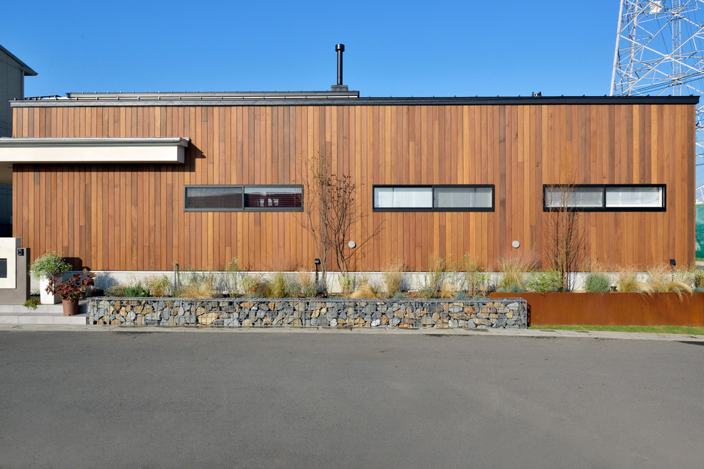 Imagen de fachada de casa marrón moderna de tamaño medio de una planta con revestimiento de madera y tejado plano